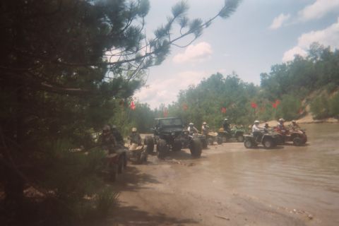 2004 Honda TRX 450 FM - A group of ATVs and a Jeep navigate a muddy trail, with red flags marking the path.