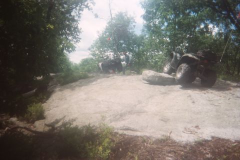 2004 Honda TRX 450 FM - An ATV navigates a challenging rocky trail with another ATV visible in the background.