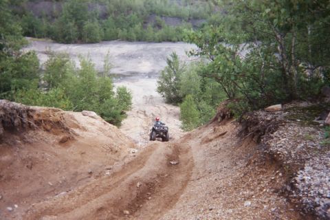 2004 Honda TRX 450 FM - A four-wheeler navigates a steep dirt track in a rocky, wooded area.