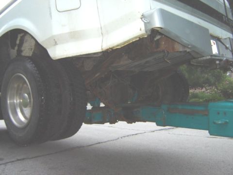 1992 Ford Bronco - The rear wheel well and frame of a white truck are visible, showing significant rust.