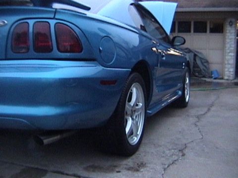 1989 Ford Mustang - Rear view of a blue convertible Mustang with the hood open, parked on concrete.