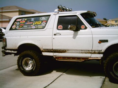 1995 Ford Bronco - This white Ford Bronco has a collection of decals on its rear quarter window and a light bar mounted on the roof.