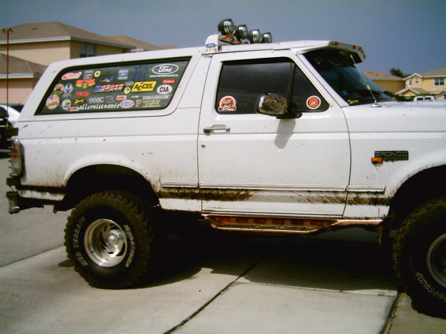 White Ford Bronco with many stickers on the rear window and a light bar on top