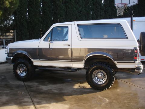 1989 Ford Bronco - Side profile of a lifted 1989 Ford Bronco with two-tone paint.