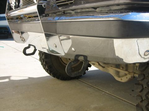 1989 Ford Bronco - The front bumper of a vehicle features two prominent tow hooks, with a tire and suspension components visible.