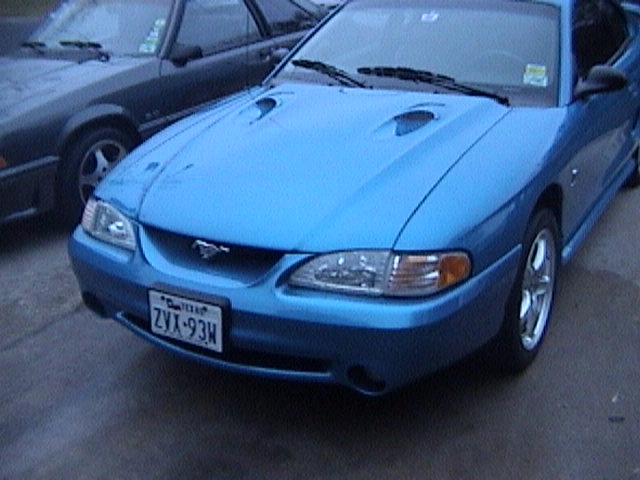 Blue Ford Mustang parked next to a dark car. License plate ZVX-93H