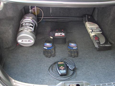 1992 Ford Taurus - The trunk of a car contains performance parts including a nitrous oxide bottle, racing gloves, and a tuning device.