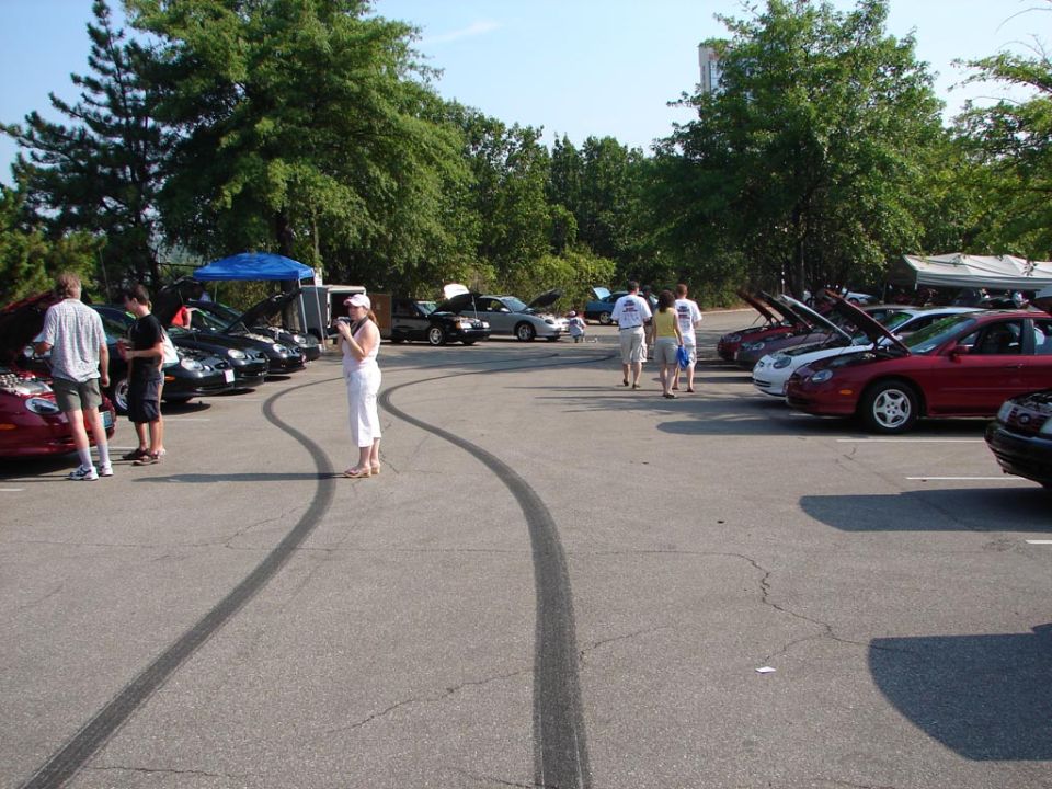 Red sedan with hood open, parked in lot with tire marks and people