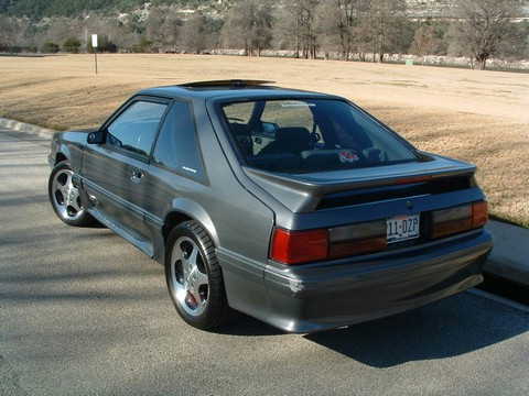 1989 Ford Mustang - This 1989 Ford Mustang coupe is shown from the rear 3/4 angle with aftermarket wheels and a spoiler.