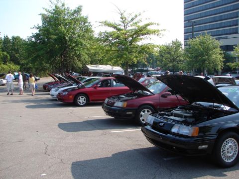 1992 Ford Taurus - Several Ford Taurus sedans are lined up in a parking lot with their hoods open, suggesting a car show or convention.