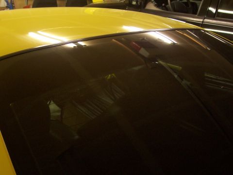 2002 Ford Mustang - The rear of a yellow vehicle is visible, parked next to another car in a garage.