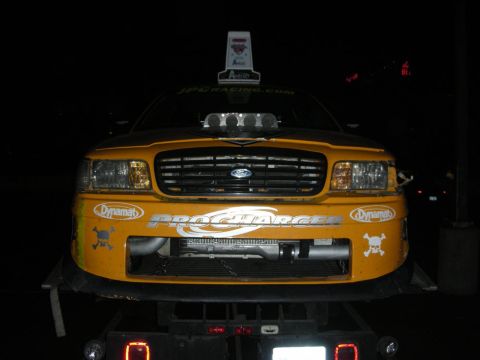 1992 Ford Crown Victoria - A modified yellow car with a prominent hood scoop and racing decals is shown from the front.