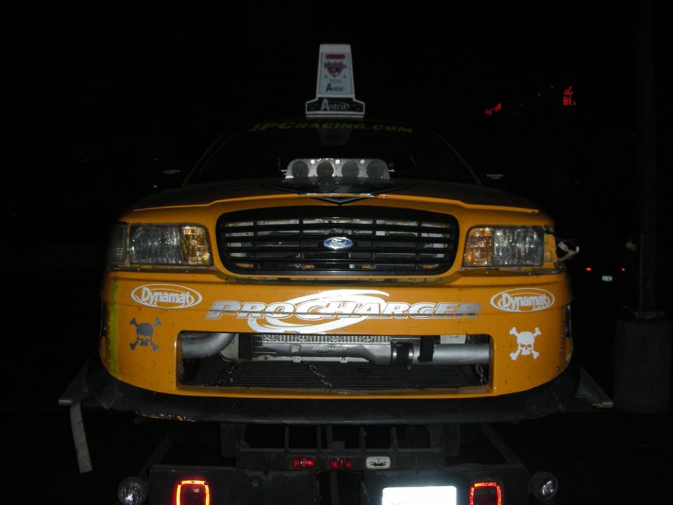 Yellow car with a large hood scoop and "PROCHARGER" decal, front view