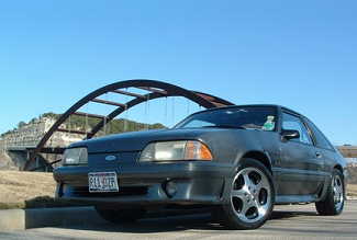 1989 Ford Mustang - This 1987-1993 Ford Mustang hatchback is shown in a three-quarter front view, aftermarket wheels and a clear blue sky.