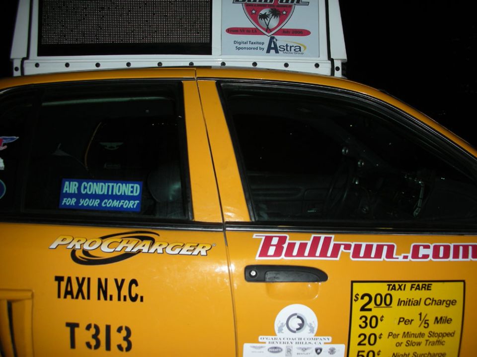 Yellow taxi cab side view, showing 'TAXI N.Y.C.' and 'Bullrun.com' decals