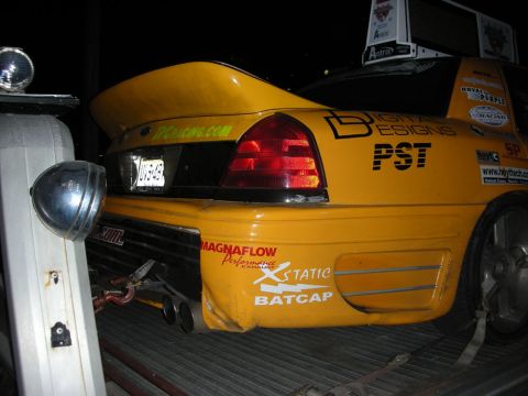 1992 Ford Crown Victoria - Rear view of a yellow car with a large spoiler and various racing decals, including 'Magnaflow Performance Exhaust'.