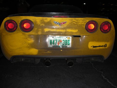 1992 Ford Crown Victoria - Rear view of a yellow Corvette showing quad exhaust pipes and a carbon fiber spoiler.