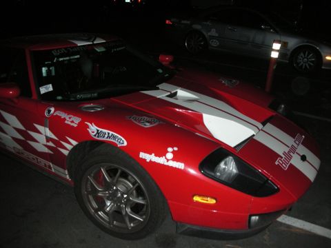 1992 Ford Crown Victoria - Red Ford GT sports car with racing decals parked next to another vehicle at night.