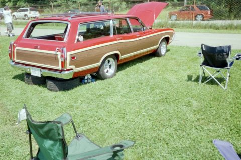 1970 Ford Ranchero - A red 1970 Ford Ranchero station wagon with wood paneling is parked on grass, with its hood open.
