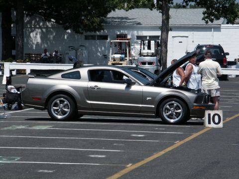 2001 Mercury Grand Marquis - A silver Ford Mustang is displayed at a car show with its hood open.