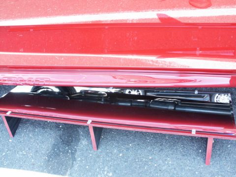 2001 Mercury Grand Marquis - Close-up view of the undercarriage of a red vehicle, showing various mechanical parts and the lower body panel.
