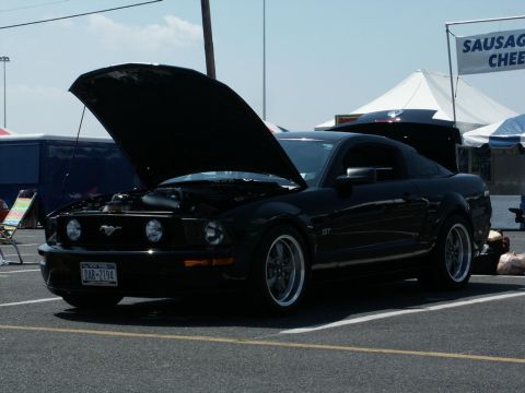 2001 Mercury Grand Marquis - A black Ford Mustang GT is parked with its hood open at an outdoor event.