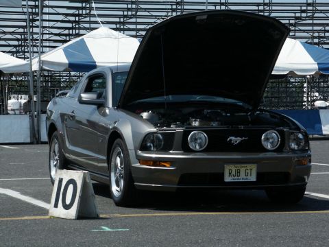 2001 Mercury Grand Marquis - A gray Ford Mustang is displayed with its hood open at a car show, showing the engine bay.