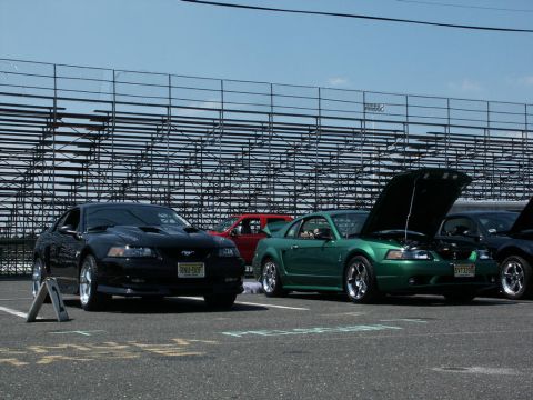 2001 Mercury Grand Marquis - Several Ford Mustangs are displayed at an outdoor car show with bleachers in the background.