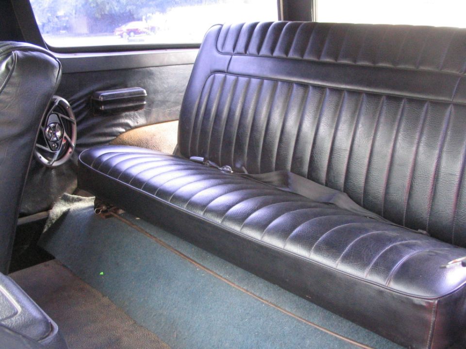 Black vinyl rear bench seat with seatbelt in a vehicle interior