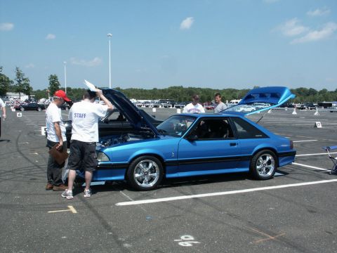2001 Mercury Grand Marquis - A blue coupe, likely a Ford Mustang, is displayed with its hood and trunk open at an outdoor event.