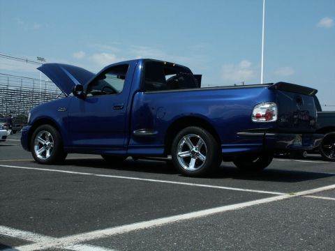2001 Mercury Grand Marquis - A blue Ford F-150 Lightning pickup truck is parked in a lot with the hood open under a clear sky.