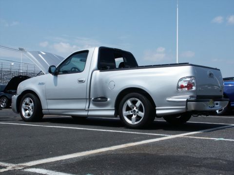 2001 Mercury Grand Marquis - A silver pickup truck is parked on asphalt with its hood open, under a clear blue sky.