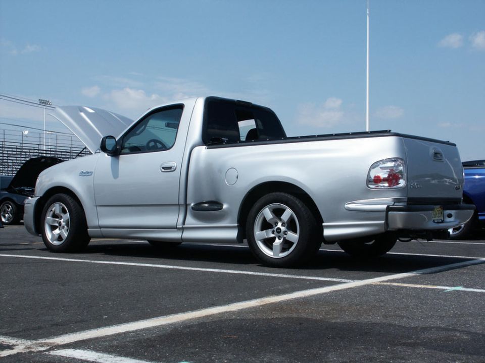Silver pickup truck with hood open, side view, parked on asphalt