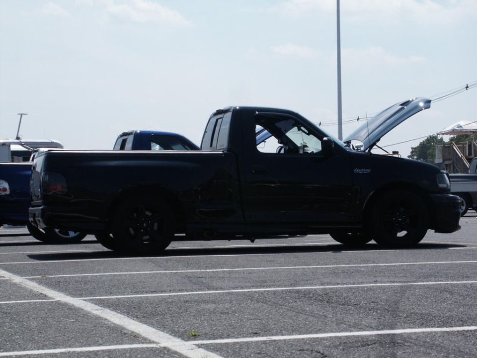 Black Ford F-150 Lightning pickup truck with hood open, parked in a lot next to other vehicles
