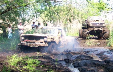 1978 Ford Bronco - Two trucks struggle through a muddy off-road course, with one being towed by the other.