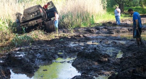 1978 Ford Bronco - A 1978 Ford Bronco is stuck deep in mud with several people nearby.
