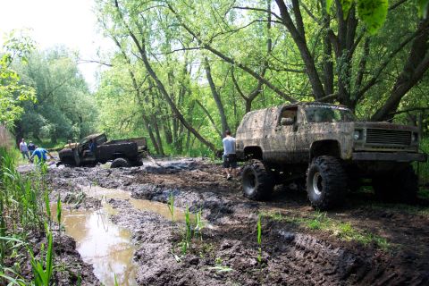 1978 Ford Bronco - Two off-road vehicles are stuck in deep mud on a wooded trail.