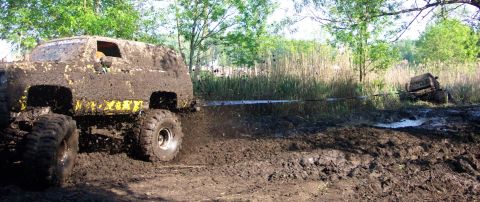1978 Ford Bronco - Off-road vehicles navigate a challenging mud course during an event.