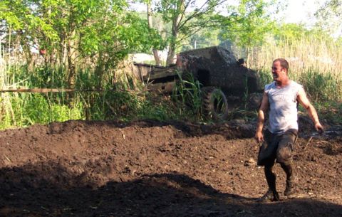 1978 Ford Bronco - A man stands in a muddy field next to a heavily soiled vehicle, suggesting a difficult off-road situation.