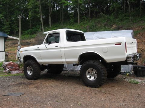 1974 Ford F-100 - This lifted 1974 Ford F-100 pickup truck features a white exterior and prominent off-road tires.