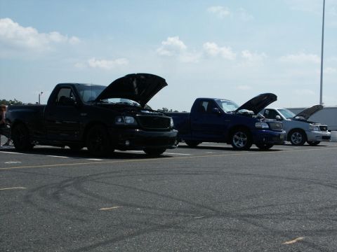 2001 Mercury Grand Marquis - Three pickup trucks and a sedan are parked in a lot with their hoods open.