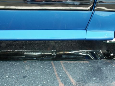 2001 Mercury Grand Marquis - Close-up view of the lower side panel and exhaust system of a blue vehicle.