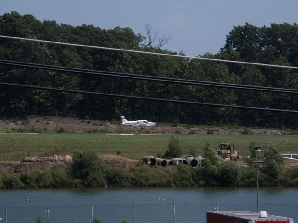 Airplane on a grassy field with a bulldozer in the background