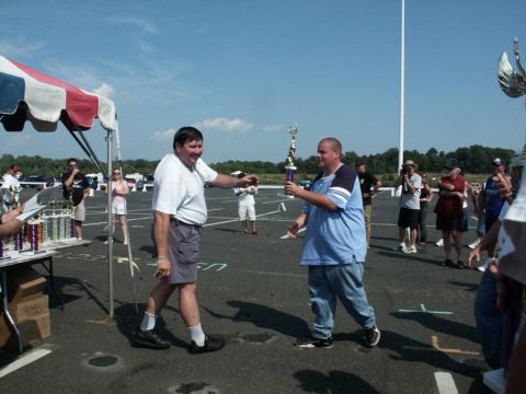 2001 Mercury Grand Marquis - Two men interact at an outdoor car show event, with trophies and vehicles visible in the background.