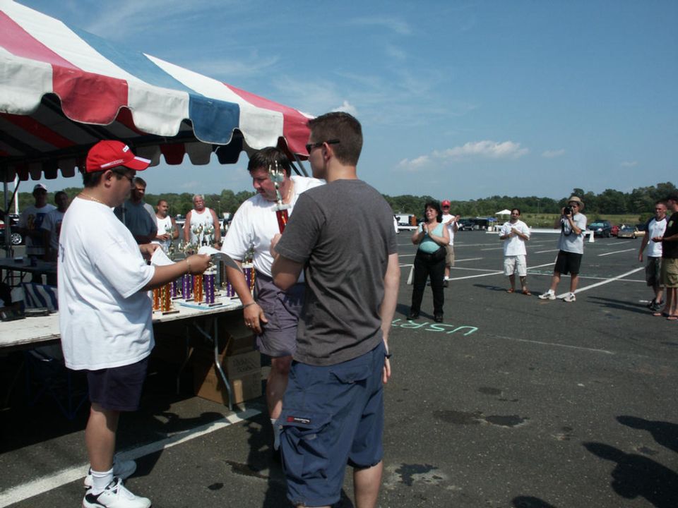 People gathered under a tent at a car show, receiving awards