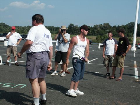 2001 Mercury Grand Marquis - Several men gather in a paved area, with cars visible in the background and a photographer documenting the event.
