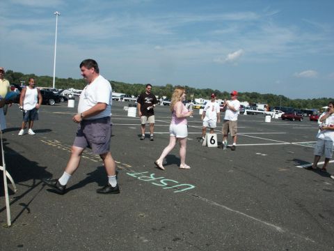2001 Mercury Grand Marquis - A car show event is underway with attendees mingling in a large parking lot under a clear sky.