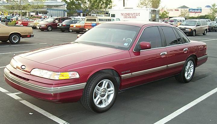 Maroon Ford Crown Victoria sedan parked in a shopping center lot, front three-quarter view