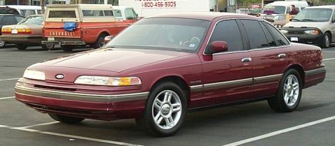 1992 Ford Crown Victoria - A maroon 1992 Ford Crown Victoria is parked in a lot with other vehicles visible.