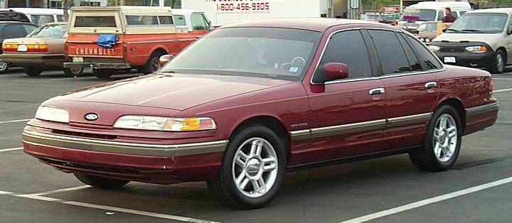 Maroon Ford Crown Victoria sedan, front 3/4 view, parked in a lot